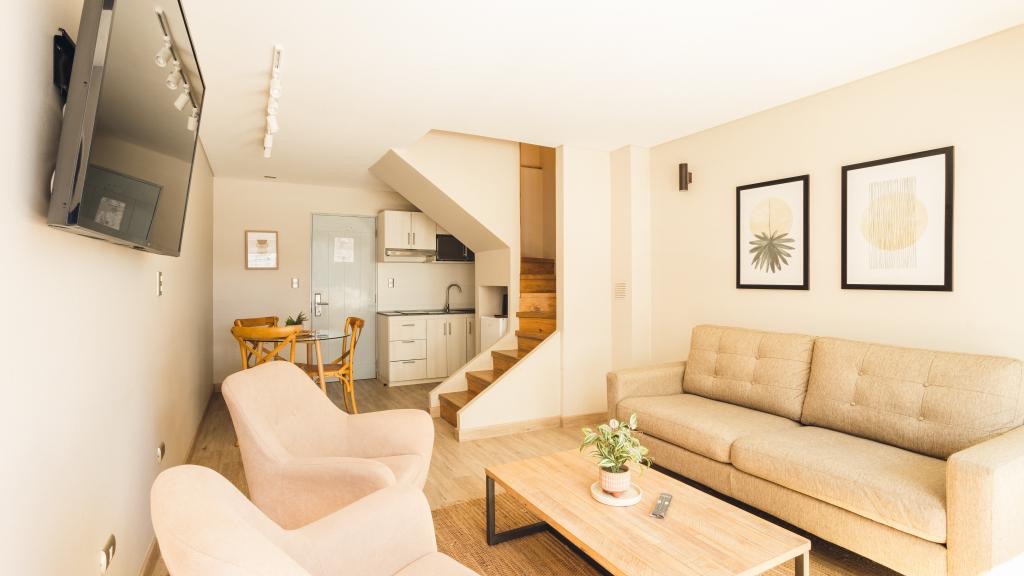 Living del departamento con sofá y escalera